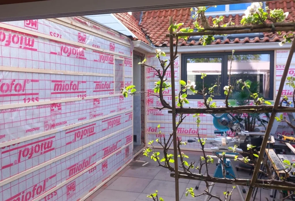 Residential courtyard with exterior wall insulation and wooden battens.